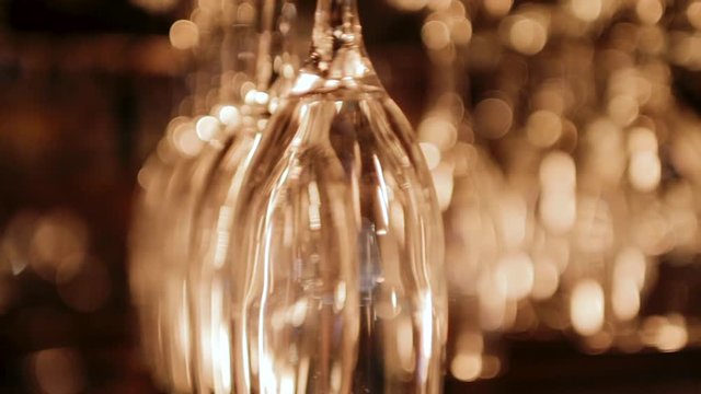 Clean wine glasses hanging upside down above a bar rack in restaurant.