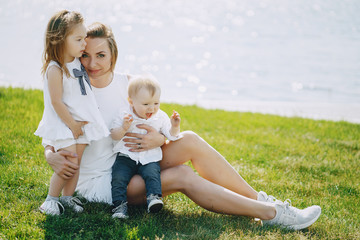 a beautiful young long-haired mom in the park with her beautiful little son and charming daughter