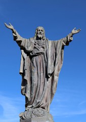 Concrete statue of Jesus with thorn encircled heart isolated on blue sky