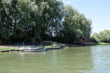 Fishing boat and old abandoned fishing ship on the river bank. Danube Delta, Romania.