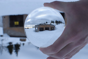 Old abandoned mountains building in crystal ball. Winter mountain landscape.