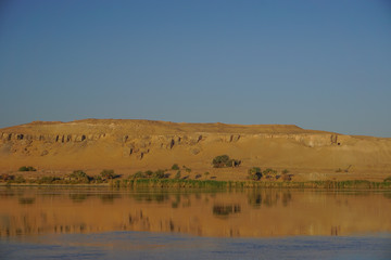 Fototapeta na wymiar Aswan, Egypt: The west bank of the Nile River on a clear, cloudless morning.
