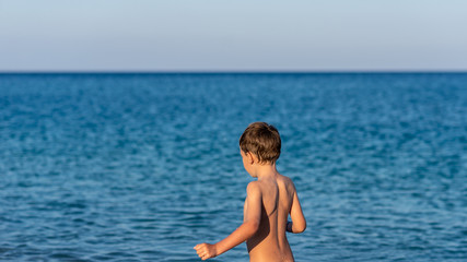 Toddler boy by a beautiful blue sea