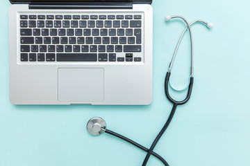 Stethoscope keyboard laptop computer isolated on blue background. Modern medical Information technology and sofware advances concept. Computer and gadget diagnostics and repair. Flat lay top view