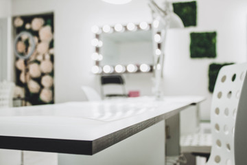 Makeup artist's workplace a mirror with lamps on a white wall and a wooden armchair