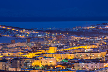 Naklejka premium Night cityscape. Top view of the port town. Bright street lighting at dusk. In the distance sea bay. Magadan, Siberia, Far East of Russia. Coast of the Sea of Okhotsk.