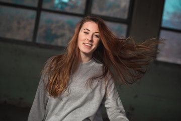 Fototapeta premium Cute, redhead teenage girl in gray sweater swinging her long hair