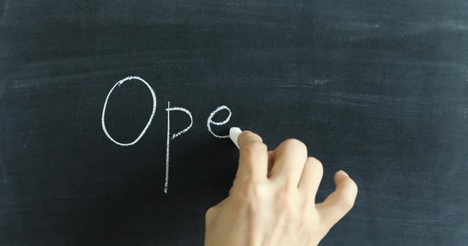 Writing OPEN and Smile sign on chalkboard with white chalk