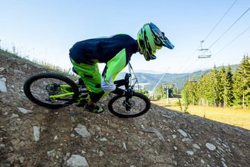 Professional athlete is riding downhill bicycle.