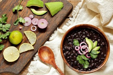 thick black bean soup or stew. Latin American or Mexican cuisine. stewed black beans served with avocado and red onion and cilantro. place for text. top view.