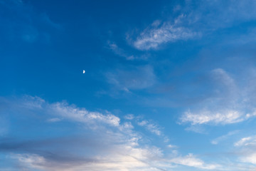 Obraz premium Moon peaking in a blue sky 