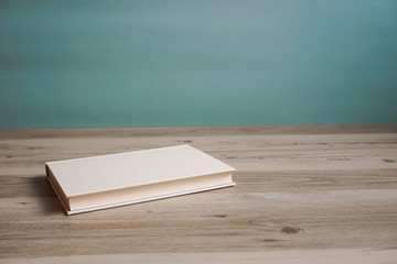 One book on a table or desk.  テーブルの上に置かれた一冊の本