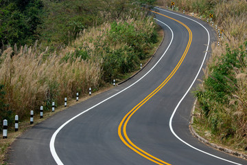 Asphalt road winding on the mountains with yellow and white traffic lines.