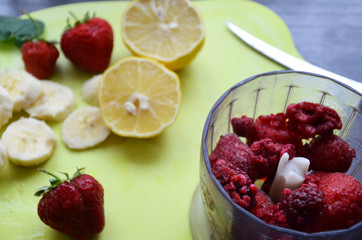 Strawberry and banana smoothie in the jar. Ingredients for making smoothies strawberry banana, frozen berries in a blender on a dark black wooden background.