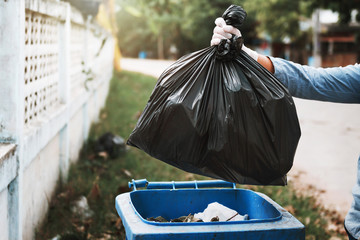 hand holding garbage black bag putting in to trash