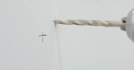 Closeup of a drill bit drilling a hole in a wall