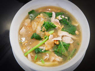 Fried noodle with pork corn and chinese Kale vegetable soaked in gravy in bowl dark background