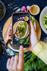Woman hands take smartphone photo of food. Phone photography of food for blog, social media. Baked vegetables, vegan family lunch, vegetarian healthy diet.
