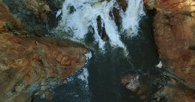Aerial view of foaming water between rocks.