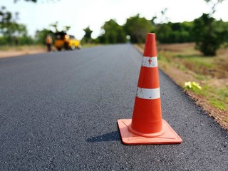 The road is under construction and has a red rubber cone on the road.