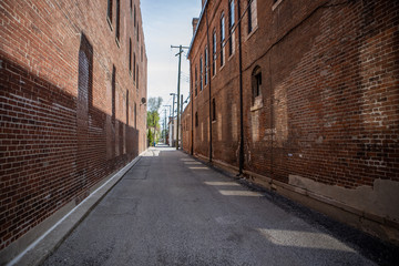 Brick buildings line gray paved alley 