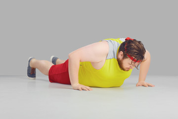 Fat funny guy with a beard doing push up goes for sports.