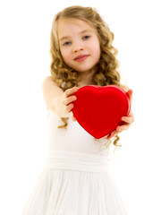 A little girl is holding a heart.