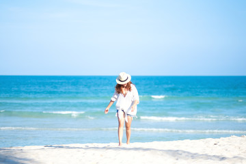 A woman strolling on the beach with the sea and blue sky background