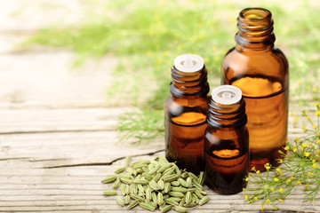 Fennel essential oil in the amber bottle with fennel flowers on the wooden board