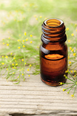 Fennel essential oil in the amber bottle with fennel flowers on the wooden board