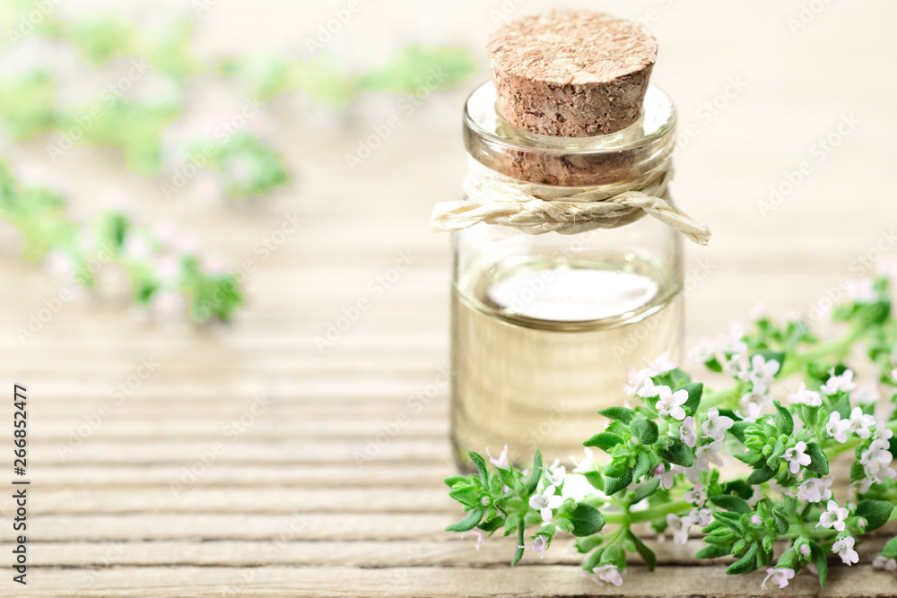 Wall mural thyme essential oil in the glass bottle, with thyme flowers.