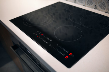 New electric stove with induction cooktop in kitchen, closeup. Modern apartment with touchscreen cooktop - obrazy, fototapety, plakaty