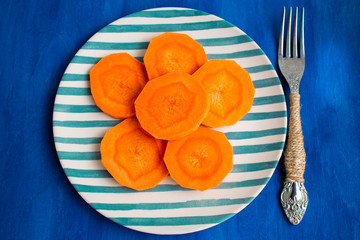  sliced ​​carrots in a plate, on a blue background