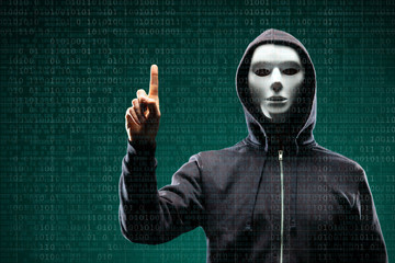 Computer hacker in mask and hoodie over abstract binary background. Obscured dark face. Data thief, internet fraud, darknet and cyber security.