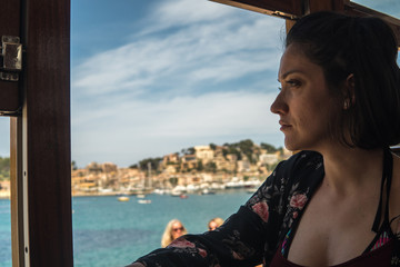 Young woman travelling alone on train. Beautiful view Port de Sóller in Mallorca island 