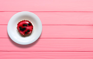 Cherry cake in a white plate on a pink wooden background