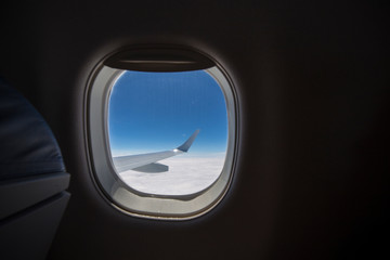 Airplane window wing view above clouds high fly flight travel plane