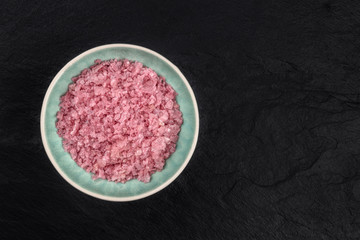Obraz na płótnie Canvas A bowl of pink Himalayan sea salt, shot from the top on a black background with a place for text