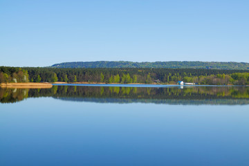 Lake with forest line mirrored in calm water surface
