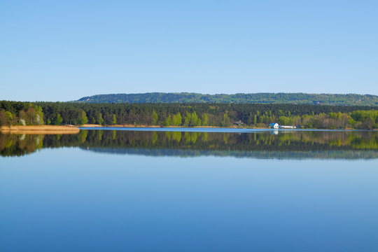 Lake with forest line mirrored in calm water surface