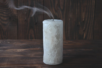 extinguished big candle in the dark. On a wooden background. Candle smoke