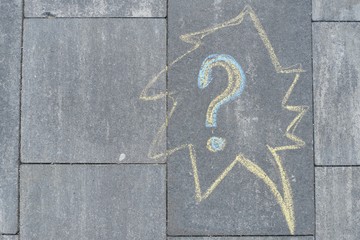 Abstract question mark drawn in crayons on gray asphalt