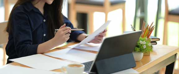 Freelancer woman working with paperwork on desk in co-working space