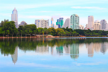 Fototapeta na wymiar Ground view of Bangkok modern office buildings, Blue sky background and lagoon at the park, Thailand