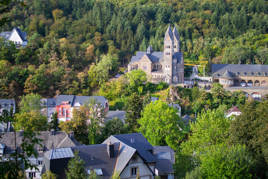 View of the Abbey of St. Maurice and St. Maurus of Clervaux (Clervaux Abbey) in Luxembourg, with houses in the middle of the forest