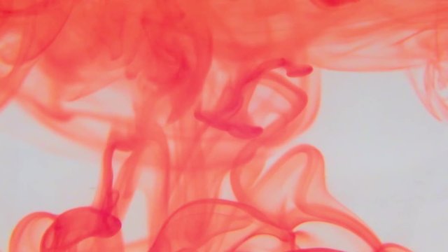 Red food coloring swirling in a container of water .