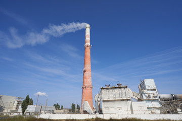 Fototapeta premium Large smoking chimney at a chemical fertilizer plant. Plant for the production of fertilizers against the blue sky