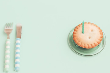 Candle in a cupcake for a holiday. The concept of a festive birthday card on green background. Space for text