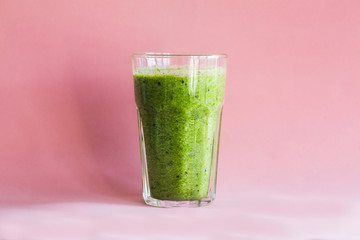 Healthy green smoothie with in a glass Cup on a pink background