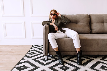 Beautiful sweet girl lying on the sofa. Golden stylish model with short red hair, plump lips,...